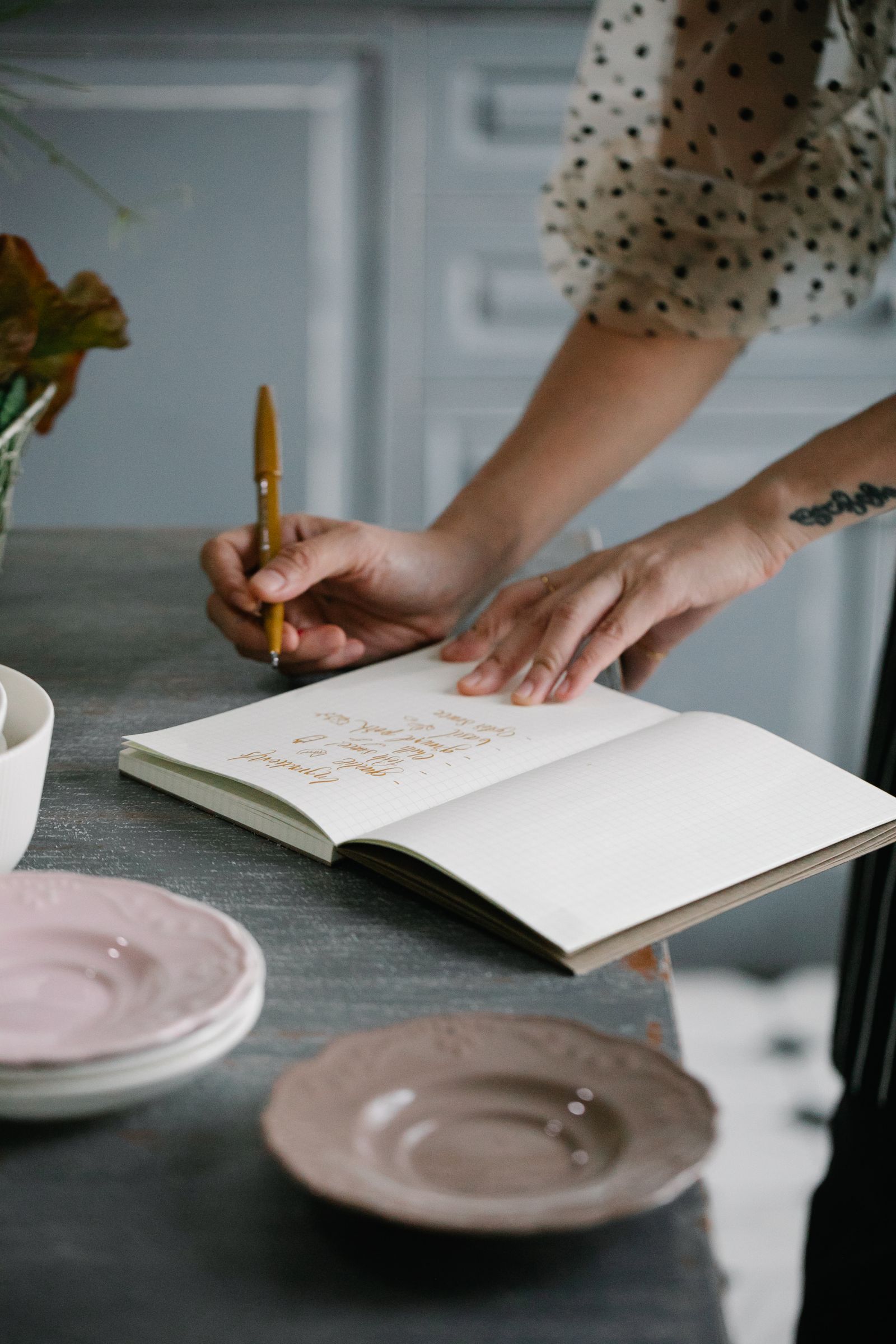Person writing the house rules for a home swap at a kitchen table