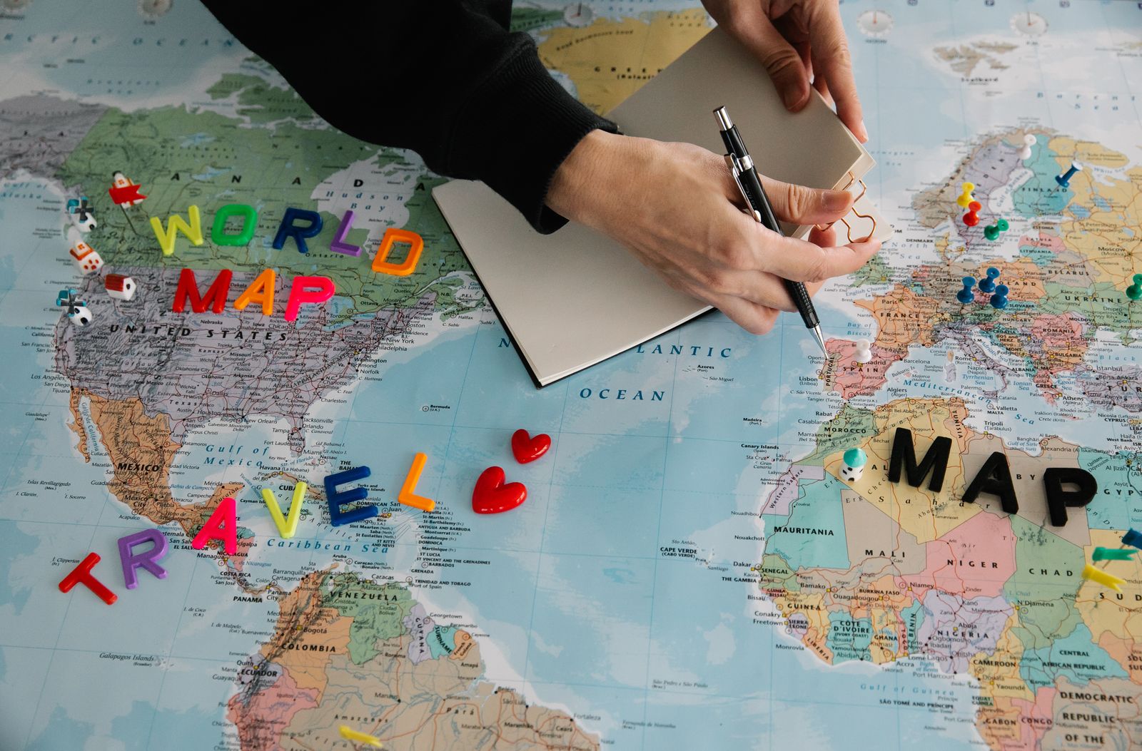 Hands marking destinations on a world map to plan an international home exchange