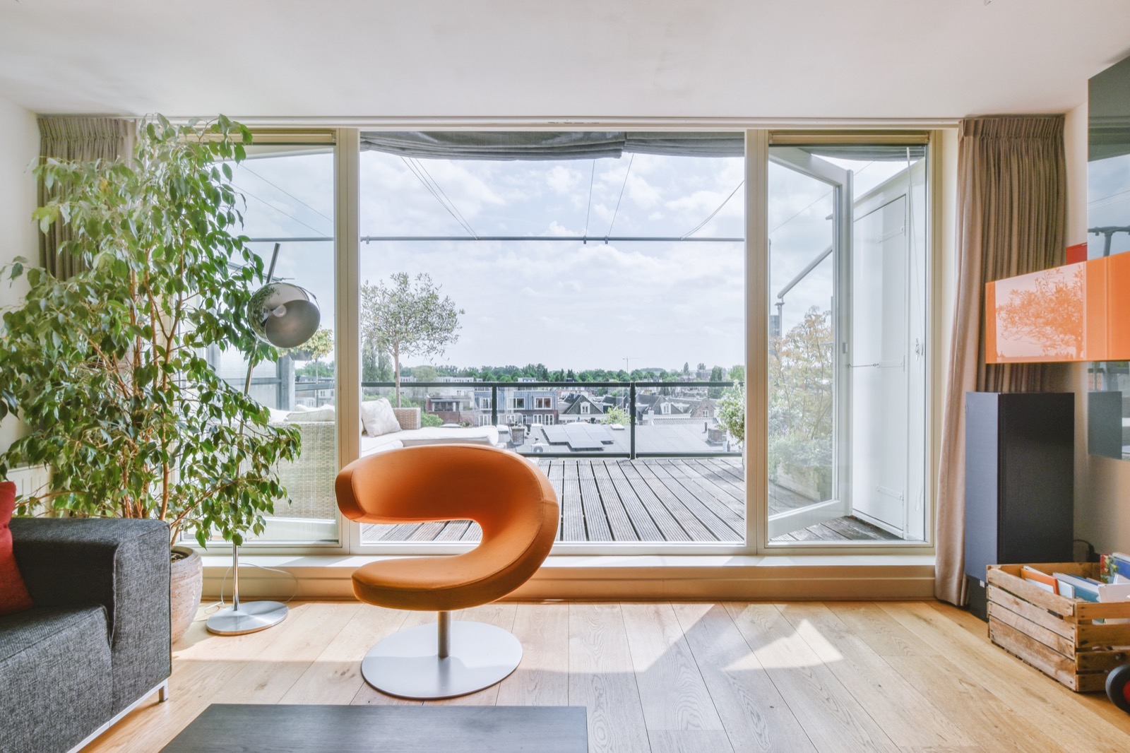 Bright apartment living room with a large glass door opening onto a balcony and the city rooftops